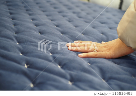 women Hand touching and pressing orthopedic mattress on bed. 115836493