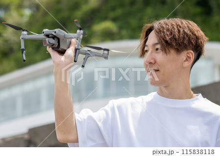 晴れの屋外でドローン撮影を楽しむ日本人男性｜ドローンイメージ 115838118