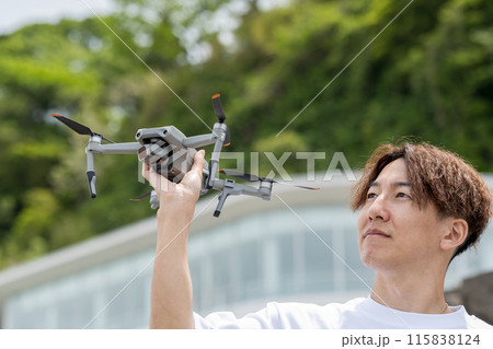 晴れの屋外でドローン撮影を楽しむ日本人男性｜ドローンイメージ 115838124