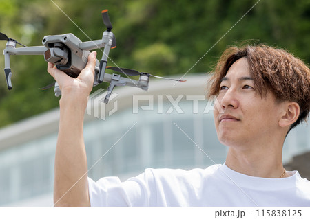 晴れの屋外でドローン撮影を楽しむ日本人男性｜ドローンイメージ 115838125