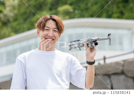 晴れの屋外でドローン撮影を楽しむ日本人男性｜ドローンイメージ 115838141