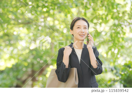 新緑の中で電話をするスーツの女性 115839542