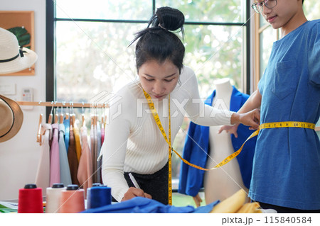 Asian women fashion designer  working and measure the customer in the showroom,  115840584