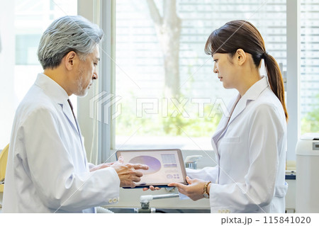 タブレットを見ながら相談する医師・研究者 タブレットを見ながら相談する医師・研究者 115841020