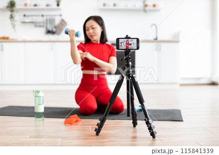 Young woman recording fitness video with smartphone at home Young woman recording fitness video with smartphone at home 115841339