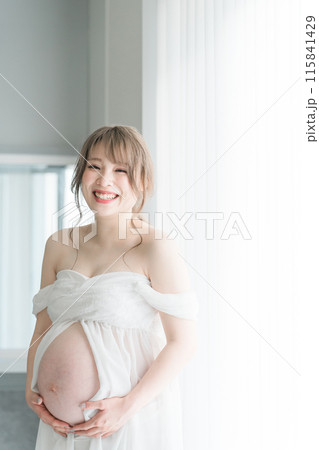 家のカーテンの前でマタニティフォトの撮影をする妊婦のアジア人女性 115841429