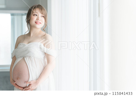 家のカーテンの前でマタニティフォトの撮影をする妊婦のアジア人女性 115841433