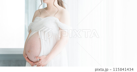 家のカーテンの前でマタニティフォトの撮影をする妊婦のアジア人女性 家のカーテンの前でマタニティフォトの撮影をする妊婦のアジア人女性 115841434