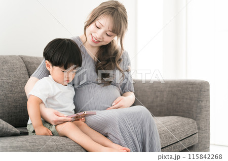 スマホを見る子供と子守をする妊娠中のママ・母親・妊婦 スマホを見る子供と子守をする妊娠中のママ・母親・妊婦 115842268