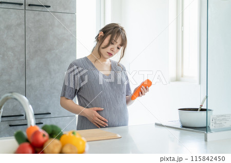 キッチンで疲れた表情で料理・調理する妊婦の女性(不満・ストレス・疲労) キッチンで疲れた表情で料理・調理する妊婦の女性(不満・ストレス・疲労) 115842450