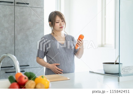 キッチンで疲れた表情で料理・調理する妊婦の女性(不満・ストレス・疲労) キッチンで疲れた表情で料理・調理する妊婦の女性(不満・ストレス・疲労) 115842451