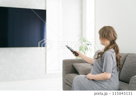 テレビのリモコンを持つ妊婦の女性（産休・産前産後休業） 115843131