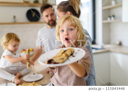Young nuclear family making pancakes together. Parents and children in kitchen, spending weekend day indoors. 115843446