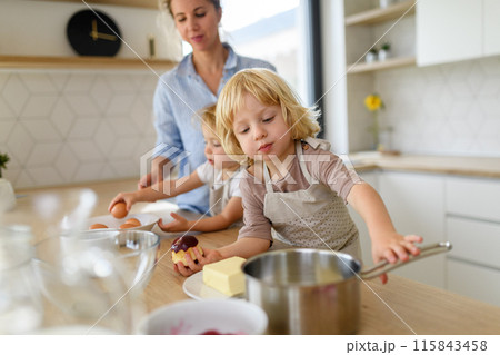 Young nuclear family making pancakes together. Parents and children in kitchen, preparing pancake batter, spending weekend day indoors. 115843458