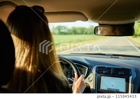 Woman driving car on country road. Back view of female driver in vehicle 115845433