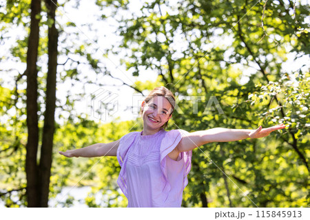 A Cheerful Woman is standing in Nature with her Arms Outstretched on a Sunny Day A Cheerful Woman is standing in Nature with her Arms Outstretched on a Sunny Day 115845913