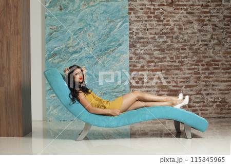 Attractive young woman make-up and long hair wearing yellow dress posing sitting Attractive young woman make-up and long hair wearing yellow dress posing sitting 115845965