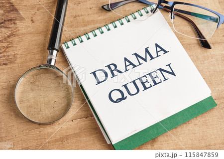 Text DRAMA QUEEN on a notebook in a composition with a magnifying glass, glasses and a pencil Text DRAMA QUEEN on a notebook in a composition with a magnifying glass, glasses and a pencil 115847859
