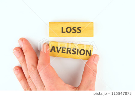 LOSS AVERSION text written on wooden blocks laid out by hand on a white background 115847873