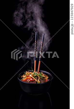 Udon noodles stir-fried with Tiger shrimps and vegetable in wok cooking pan on dark background Udon noodles stir-fried with Tiger shrimps and vegetable in wok cooking pan on dark background 115847929