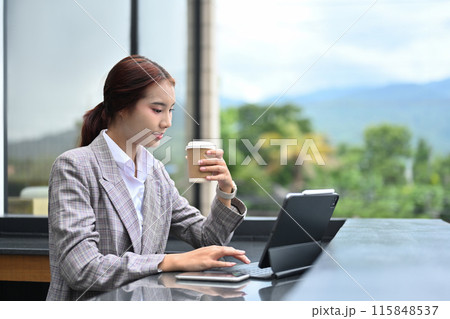 Attractive businesswoman enjoying a cup of coffee and using digital tablet at building terrace 115848537