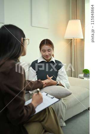 Psychotherapist holding patient hands and giving support during therapy session at clinic Psychotherapist holding patient hands and giving support during therapy session at clinic 115848664