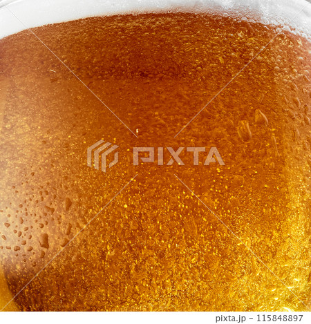 Cold beer in glass with condensation droplets. Bright golden color and lighting make drink look appealing and refreshing. Cold beer in glass with condensation droplets. Bright golden color and lighting make drink look appealing and refreshing. 115848897