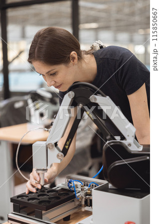 Engineer women learning education in Industrial Robotics program with robot arm simulation model in university engineering lab classroom. 115850667