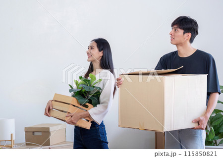 Young Couple Moving into New House, Carrying Boxes and Plants, Starting Fresh in Their Modern Home Young Couple Moving into New House, Carrying Boxes and Plants, Starting Fresh in Their Modern Home 115850821
