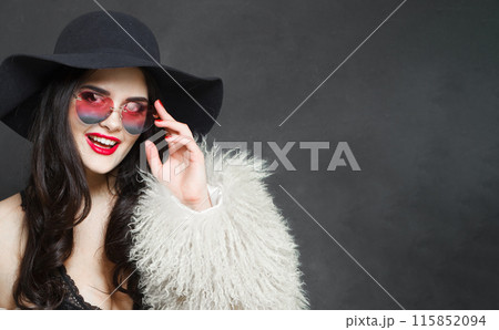 Laughing young adult woman fashion model with bright make-up and long wavy hair wearing blue hat Laughing young adult woman fashion model with bright make-up and long wavy hair wearing blue hat 115852094