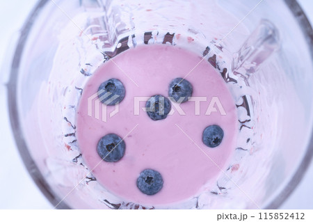 Mixed sweet blueberries with yoghurt and seeds in a blender cup, top view. Mixed sweet blueberries with yoghurt and seeds in a blender cup, top view. 115852412