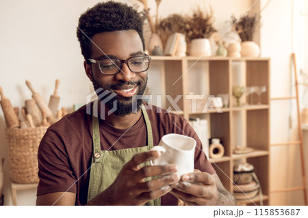 Dark-skinned sculptor working in his workshop and looking involved 115853687