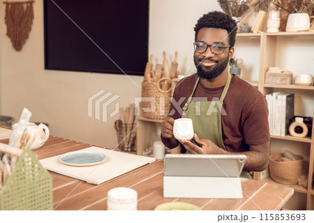 Dark-skinned sculptor demonstrating a new cup to the audience on online tutorial 115853693