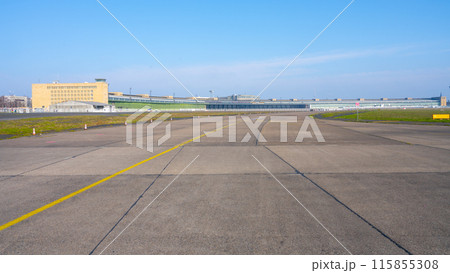 Clear blue skies over the historic Berlin Tempelhof Airport in Germany, showcasing the vast airport tarmac and iconic terminal building with hangars. Clear blue skies over the historic Berlin Tempelhof Airport in Germany, showcasing the vast airport tarmac and iconic terminal building with hangars. 115855308