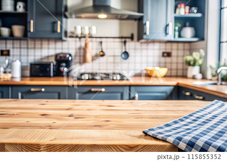 In the kitchen, there is a wooden table with a checkered towel on top of it 115855352