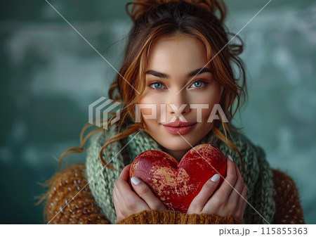 Young Woman Holding a Heart-Shaped Object in Cozy Winter Clothing 115855363
