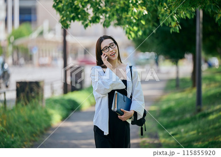 スマホで電話しながら歩く若い女性 スマホで電話しながら歩く若い女性 115855920