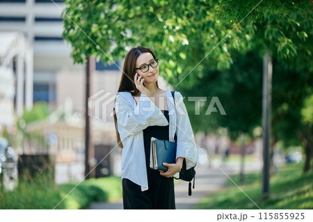 スマホで電話しながら歩く若い女性 スマホで電話しながら歩く若い女性 115855925