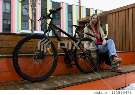 Woman Sitting on Bench Next to Bike 115859478
