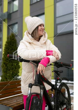Woman Standing Next to Bike in Snow 115860058