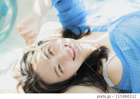 仰向けに寝転がる青い服の女性 115860312