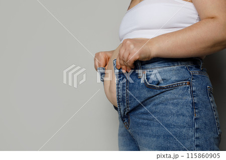 Female person trying to zip up her denim pants on white background, dieting concept 115860905