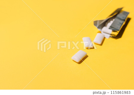 Chewing gum pads spilled out of a foil package on a yellow background 115861983