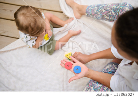 Mom and toddler playing with colorful shapes outdoors on blanket Mom and toddler playing with colorful shapes outdoors on blanket 115862027