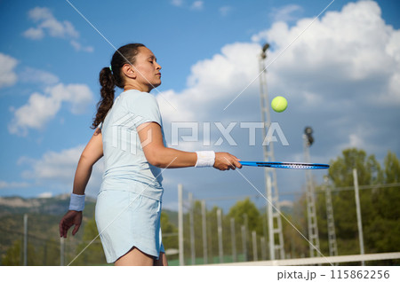 Woman in her 40s playing tennis on the court on a sunny day 115862256