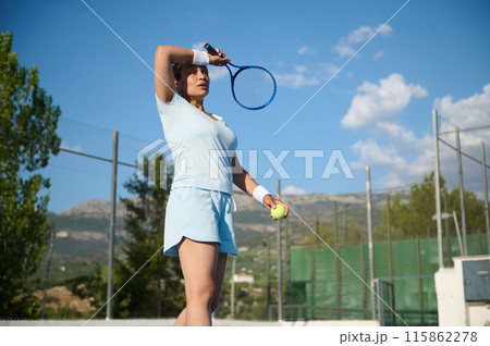 Woman in her 40s playing tennis on an outdoor court on a sunny day 115862278