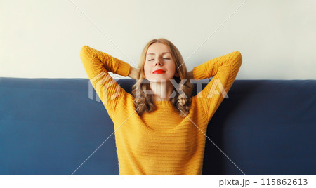 Happy relaxed young woman enjoying at home, satisfied girl sitting on the couch in living room 115862613