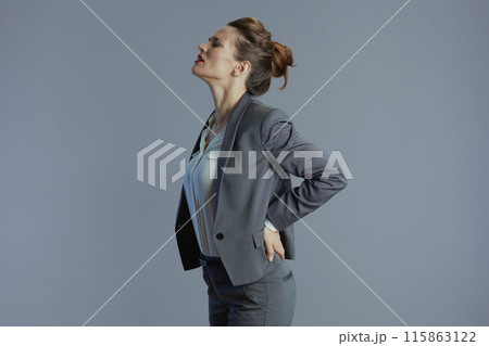 stressed woman employee having back pain isolated on grey 115863122