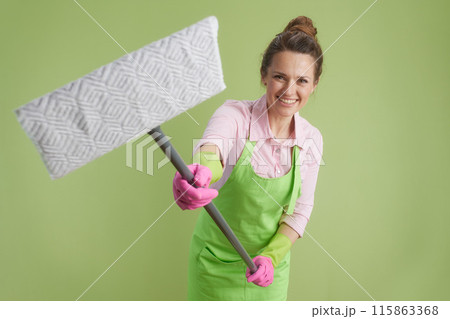 happy woman in green apron and rubber gloves isolated on green happy woman in green apron and rubber gloves isolated on green 115863368