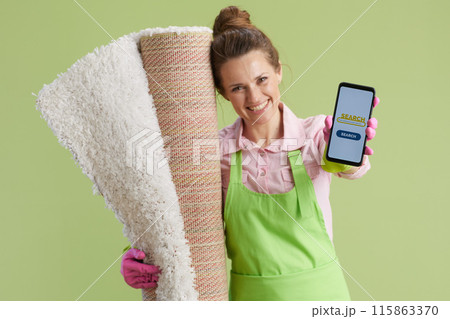 woman showing smartphone screen against green woman showing smartphone screen against green 115863370